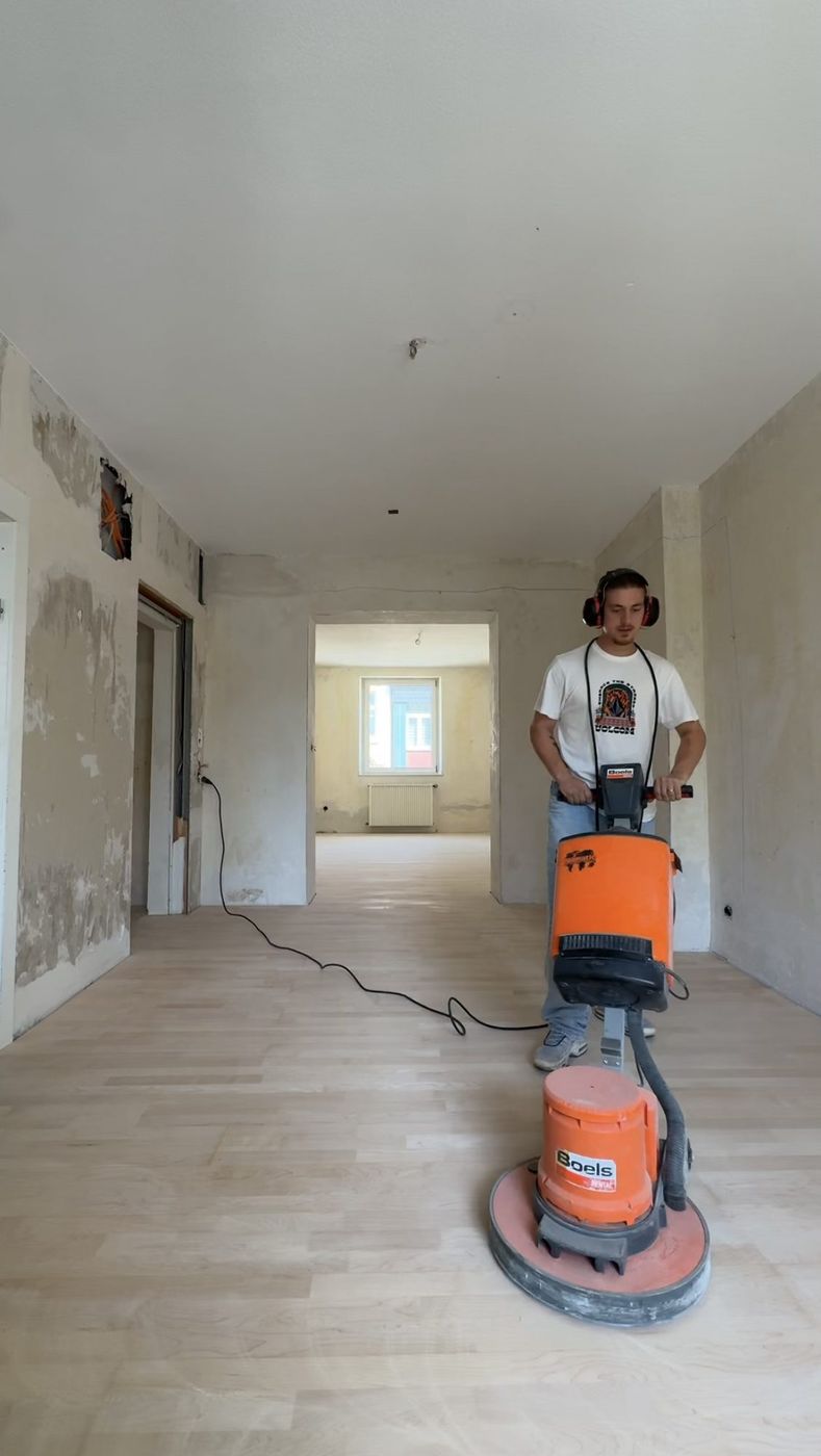 Ramon Pessoa beim Schleifen eines Holzbodens in einem leeren Raum